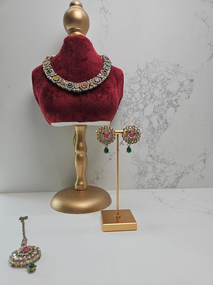Jewelry set including a necklace, earrings, and bangles on a mannequin and stand against a marble background.