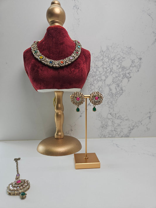 Jewelry set including a necklace, earrings, and bangles on a mannequin and stand against a marble background.