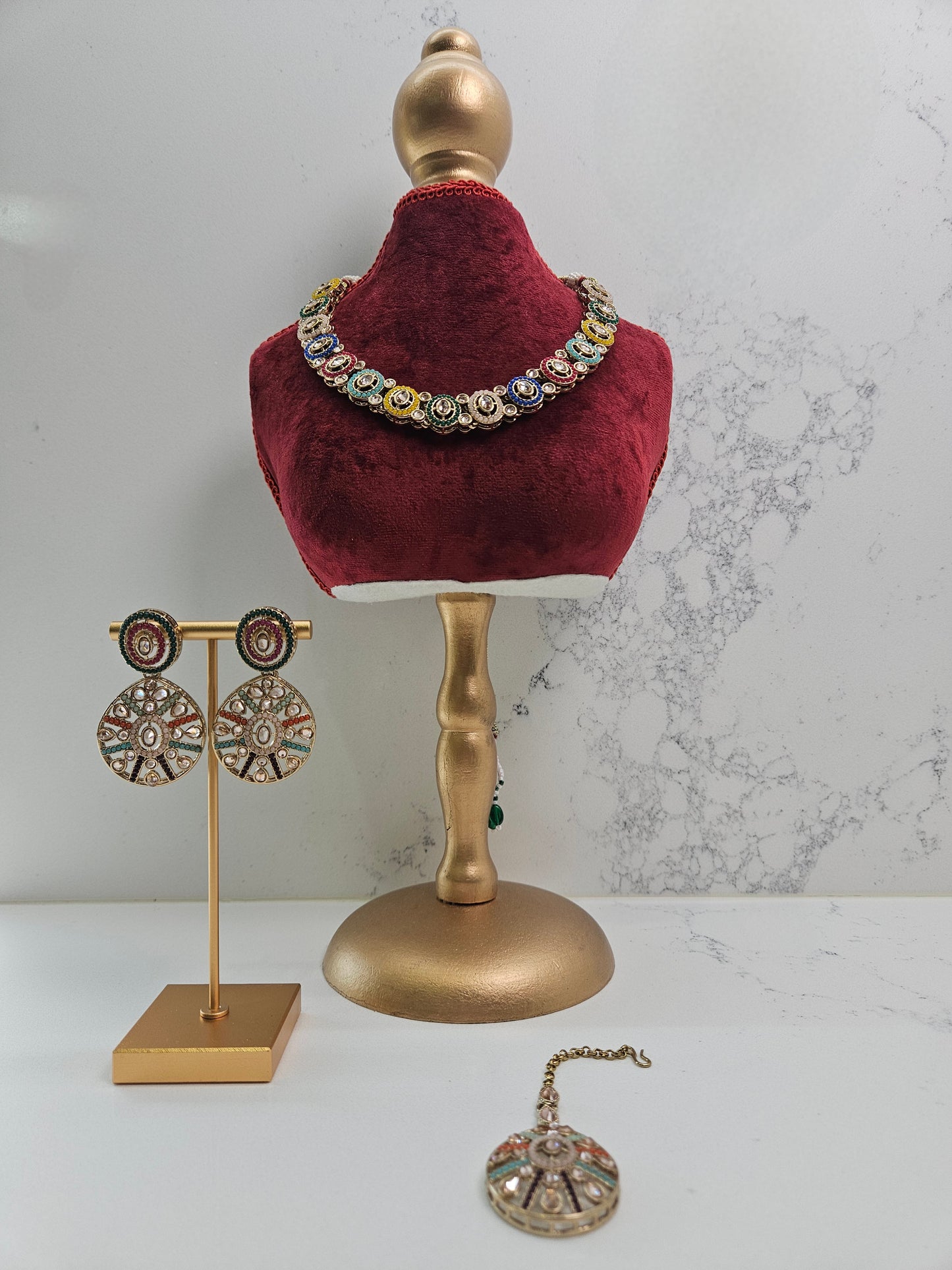 Jewelry set including earrings and a necklace on a mannequin bust with a marble background.