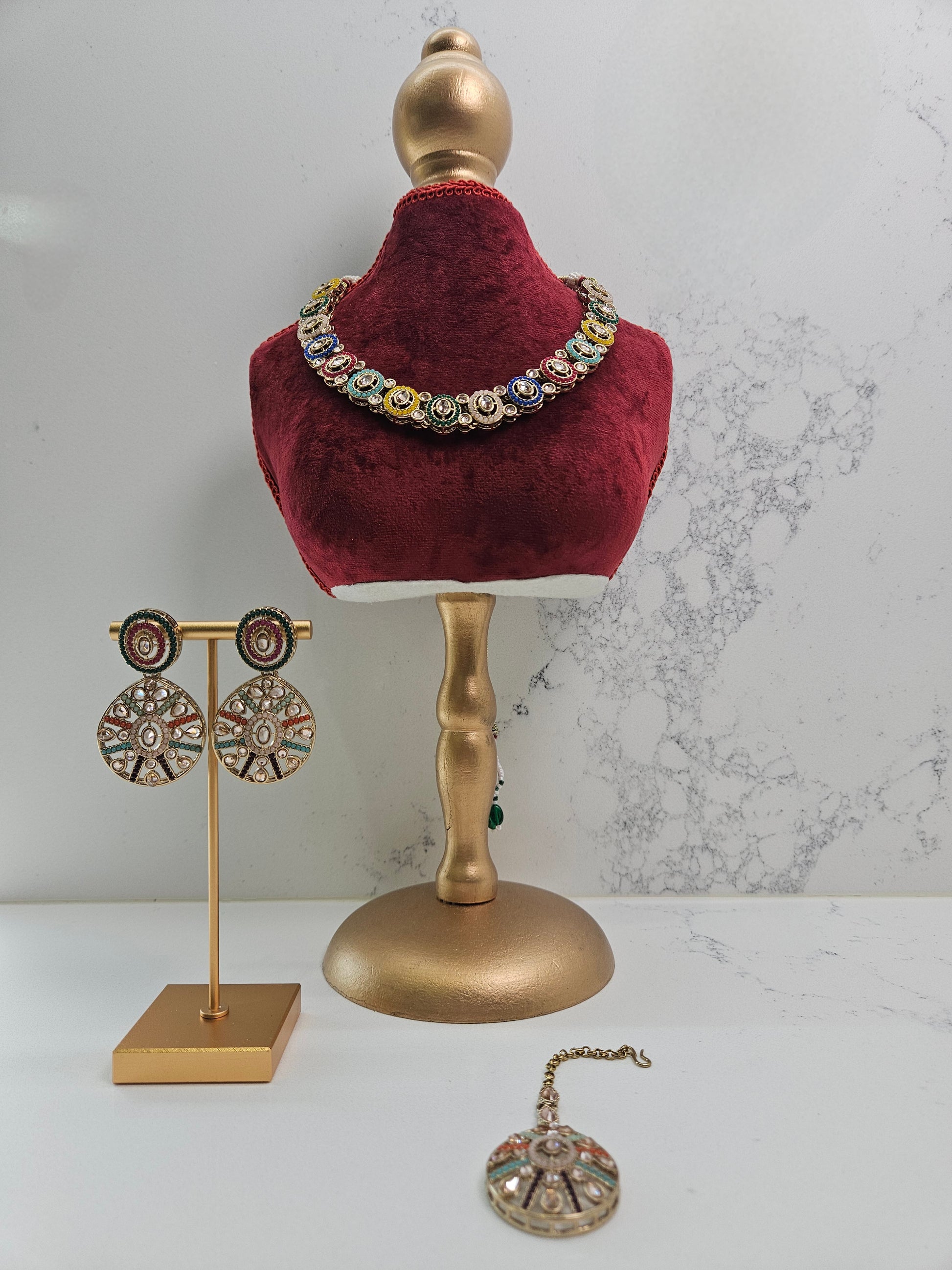 Jewelry set including earrings and a necklace on a mannequin bust with a marble background.