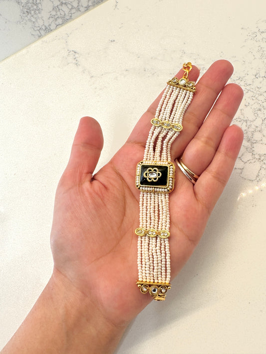 Hand holding a beaded bracelet with gold accents on a light background