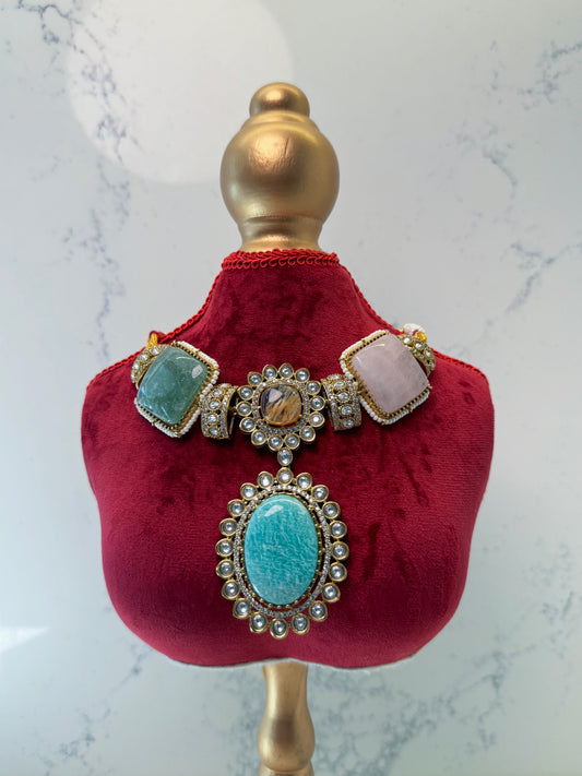 Decorative necklace with turquoise stones on a red velvet stand against a marble background